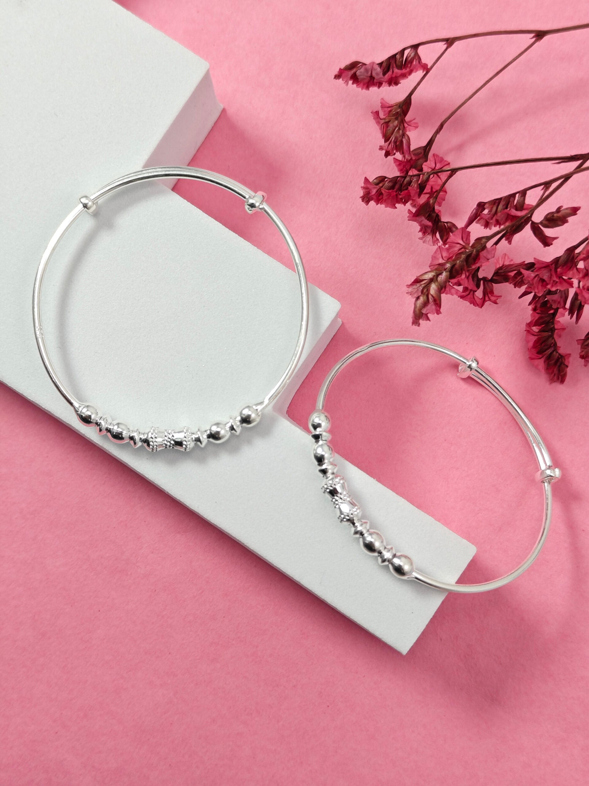 Silver hoop earrings with bead detailing on a pink background